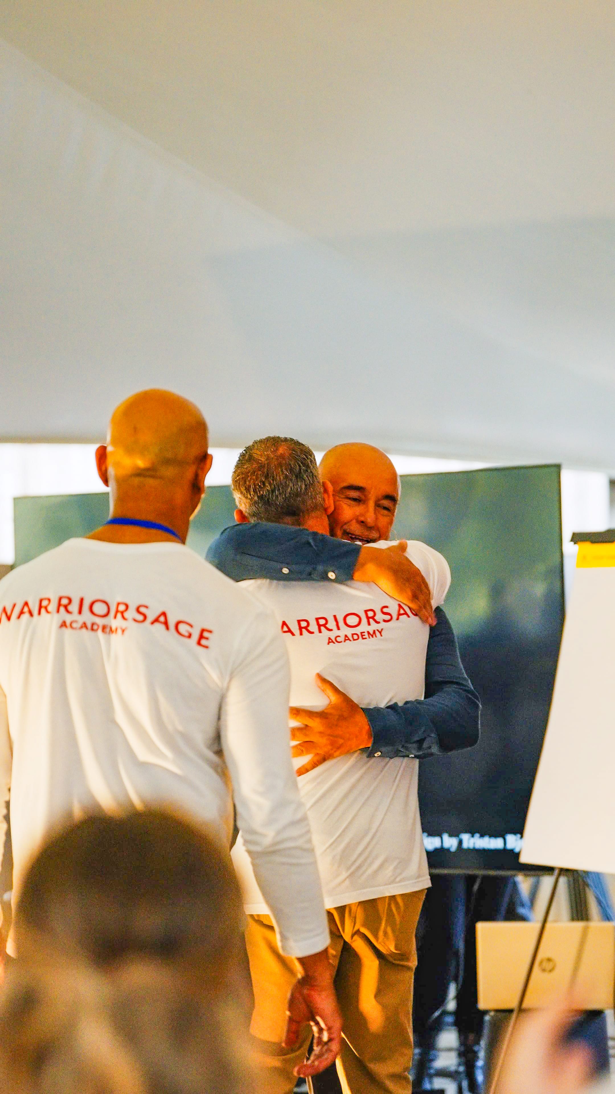 Three participants embracing in group hug indoors