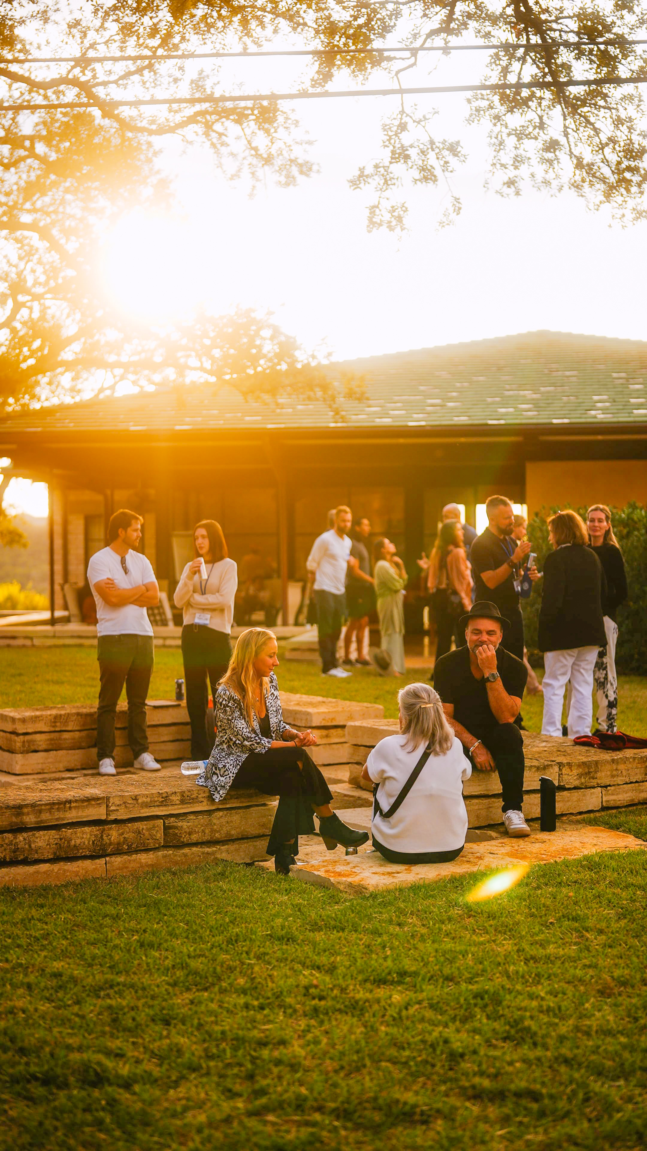 Participants socializing outdoors during evening gathering with golden hour lighting